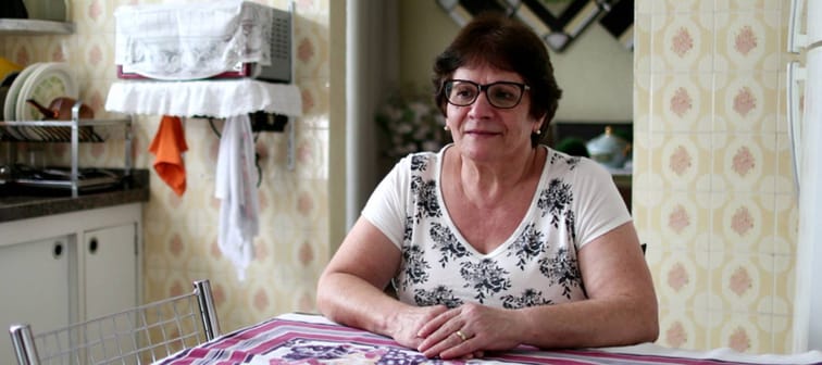 Pensive older woman sitting at home at her kitchen table.